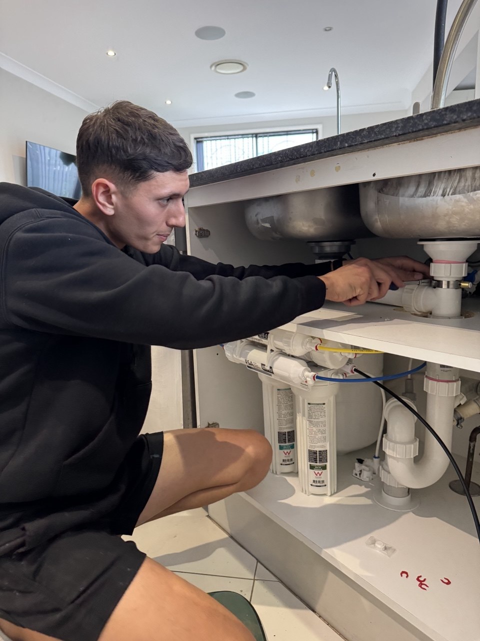 Plumber fitting reverse osmosis filter under kitchen sink Sydney